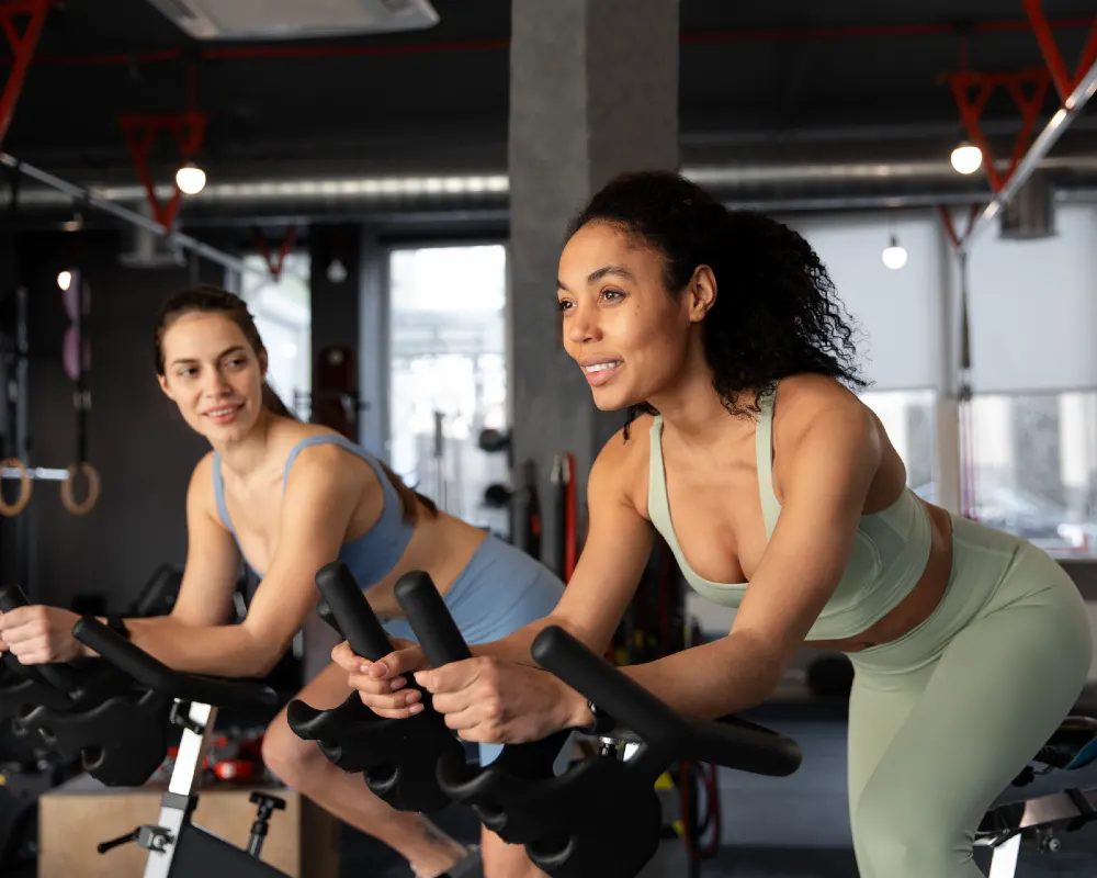 Women’s Fitness Clubs of Canada Ajax members enjoying a spin class in the modern cycling studio, focused on wellness and strength training in a women-only environment.